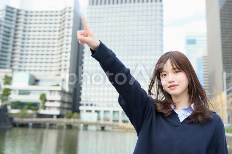 ビル街で大きく指をさす女子高生 高校生,女子高生,指さしの写真素材
