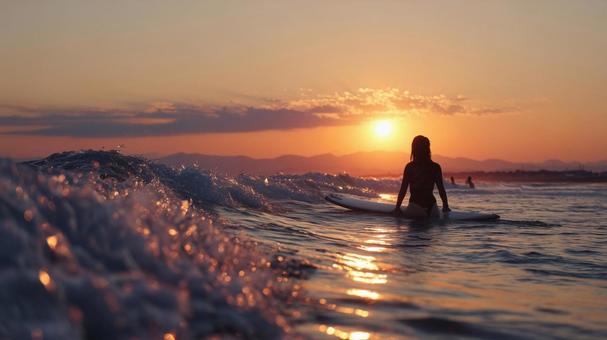 夕暮れの海で最後の波に乗るサーファー女性 夕暮れの海で最後の波に乗るサーファー女性の写真