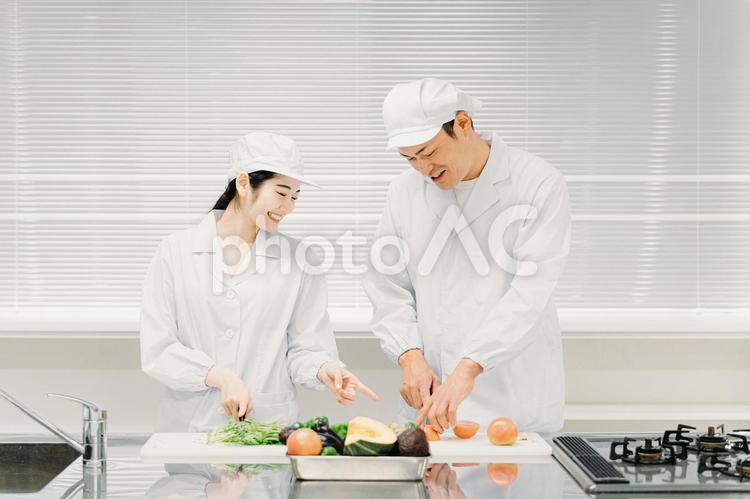 食品工場で働く男女の調理員（教える） 食品工場,給食センター,調理師の写真素材