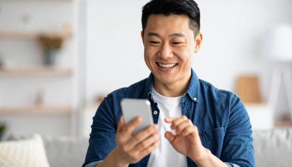 スマホを操作し微笑む男性のポートレート スマホを操作し微笑む男性のポートレートの写真