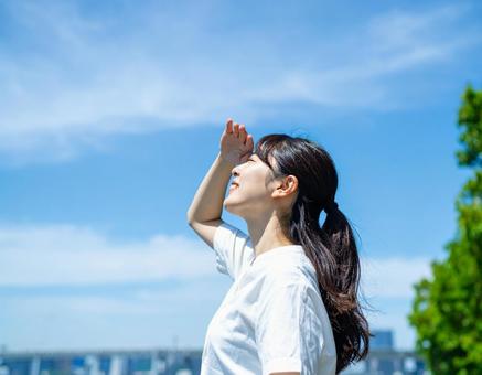 空を見上げて眩しい顔をする女性 空を見上げて眩しい顔をする女性の写真