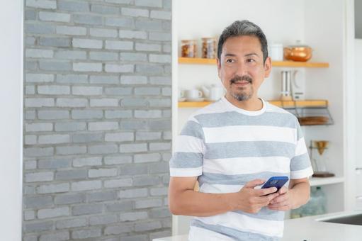 キッチンでスマホを使うミドルの男性 キッチンでスマホを使うミドルの男性 男性,スマホ,ミドルの写真素材
