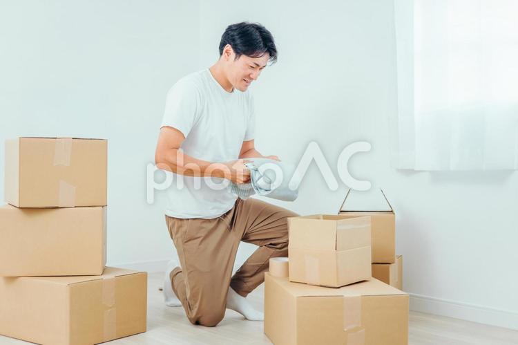 段ボールから洋服を出す男性 ダンボール,引越し,荷物の写真素材