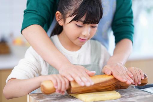 キッチンで生地をのばす子どものクッキングシーン 女の子,日本人,めん棒の写真素材