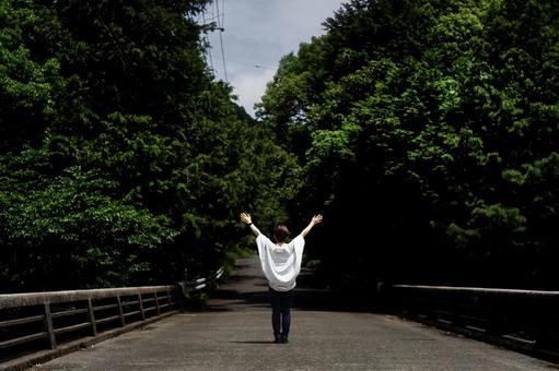 <素材>新緑の初夏の山道を散歩する女性 <素材>新緑の初夏の山道を散歩する女性 女性,橋,道路の写真素材