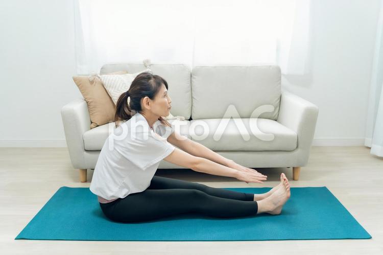 部屋でヨガをするミドル世代の女性（前屈） 体前屈,ヨガ,前屈の写真素材