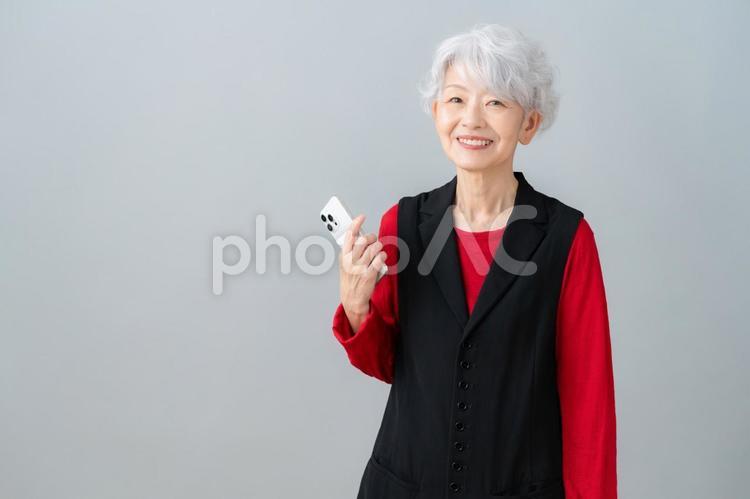 スマホを見るグレーバックのシニアの女性 シニア,女性,スマホの写真素材