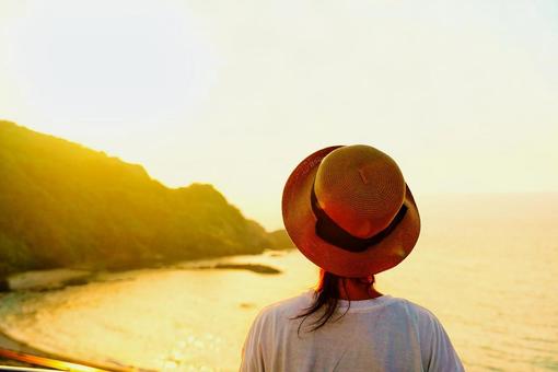 夕焼け空を見ながらリラックスする女性 夕焼け空を見ながらリラックスする女性 女性,夕日,海の写真素材