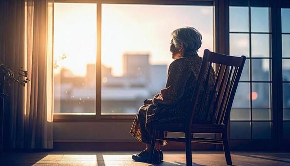椅子に座って窓の外を見る高齢女性 椅子に座って窓の外を見る高齢女性の写真
