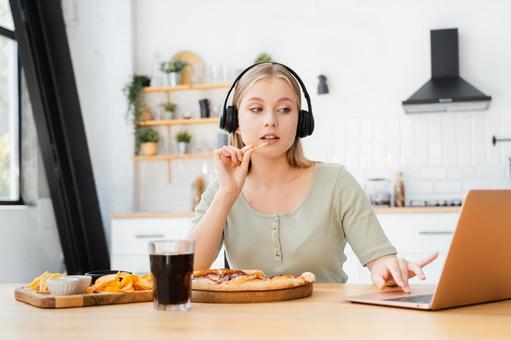パソコンを見ながらポテトを食べるヘッドフォンの女性 パソコンを見ながらポテトを食べるヘッドフォンの女性 女性,人物,ジャンクフードの写真素材