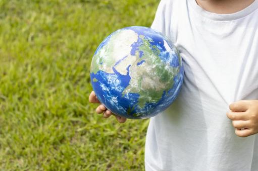 地球儀を持って草原で立っている男の子 男の子,地球,地球儀の写真素材