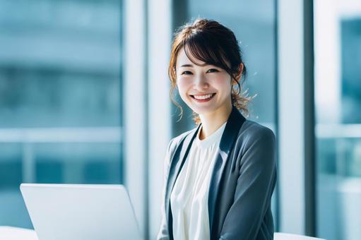 ノートパソコンを使用する女性会社員の写真