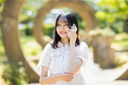 スマホを耳に当て穏やかな表情の若い女性 女性,公園,庭園の写真素材