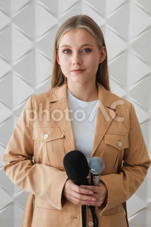 両手でマイクを持つカメラ目線の女性 女性,取材,マイクの写真素材