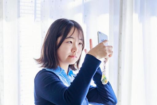 窓際で自撮りをする若い女性 女性,スマホ,自撮りの写真素材