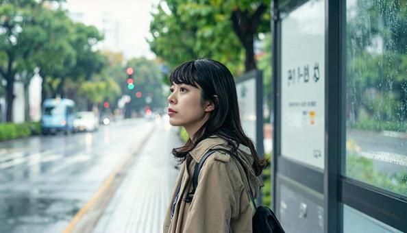 雨の中バス停でバスを待つ日本人女性 雨の中バス停でバスを待つ日本人女性の写真