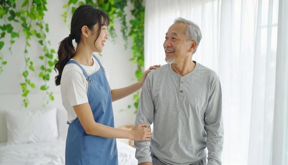 シニア男性の起き上りを補助するヘルパー シニア男性の起き上りを補助するヘルパーの写真