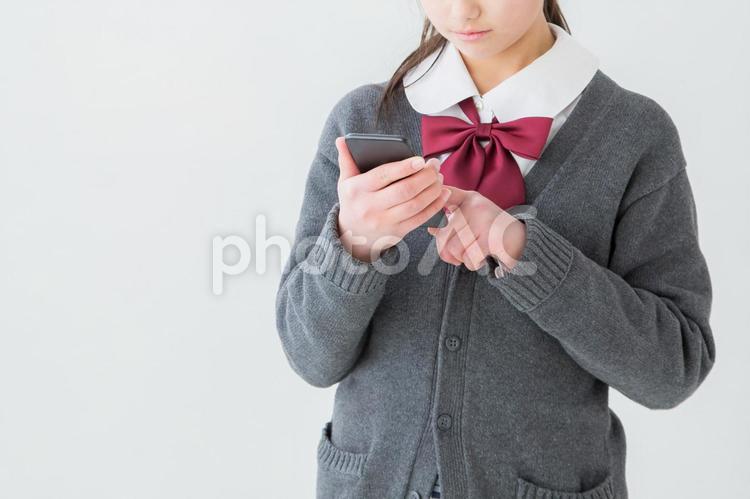 携帯電話を見る制服を着た女の子 スマホ,勉強,ゲームの写真素材