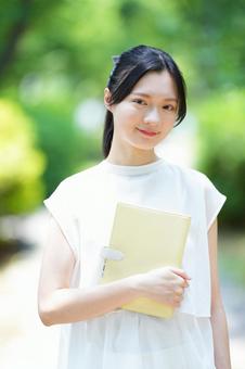 白いノースリーブワンピースの女性が本を読むの写真