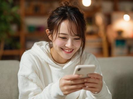 リビングで楽しそうにスマホする女性 リビングで楽しそうにスマホする女性の写真
