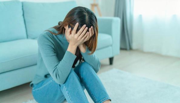 部屋で落ち込んで座る日本人女性の横顔 部屋で落ち込んで座る日本人女性の横顔の写真