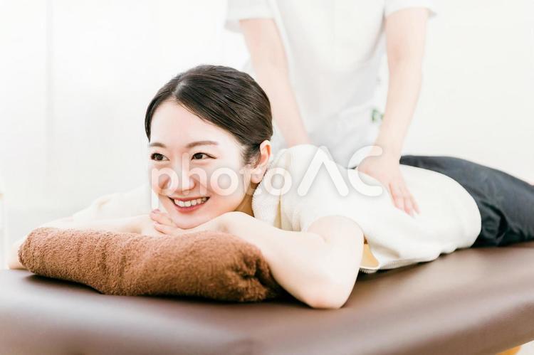 整骨院で腰を揉むマッサージ師の女性 整体,マッサージ,骨盤矯正の写真素材