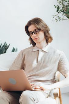 リビングで膝の上でノートパソコンを使う若い男性 男性,外国人,欧米人の写真素材