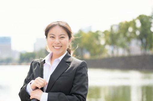 ビル街でカメラ目線のスーツの女性 ビル街でカメラ目線のスーツの女性 日本人,女性,20代の写真素材