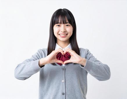 手でハートマークを作る女子生徒 手でハートマークを作る女子生徒の写真