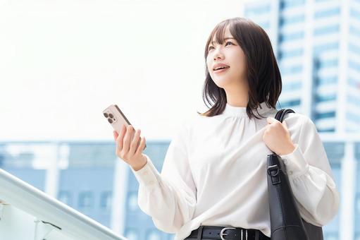 屋外でスマホを持つ女性・ビジネスウーマン 屋外でスマホを持つ女性・ビジネスウーマン 女性,スマホ,スマートフォンの写真素材