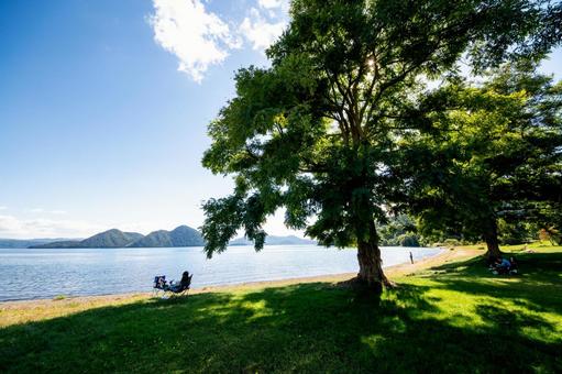 人々が木陰で憩う、初秋の洞爺湖畔 人々が木陰で憩う、初秋の洞爺湖畔 洞爺湖,湖畔,水辺の写真素材