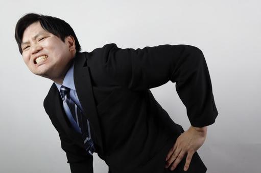 腰を押さえて苦悶の表情を浮かべる 腰を押さえて苦悶の表情を浮かべる ビジネスマン,腰痛,腰の写真素材