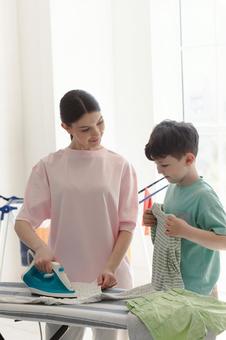 アイロンする女性と畳む男の子 アイロンする女性と畳む男の子 親子,女性,男の子の写真素材