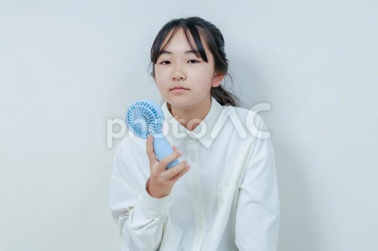 右手に扇風機を持ったカメラ目線の女の子 女性,小学生,少女の写真素材