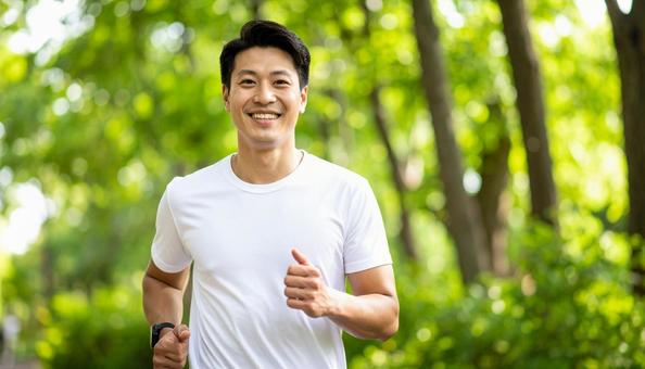 公園でジョギングをする笑顔の日本人男性 公園でジョギングをする笑顔の日本人男性の写真