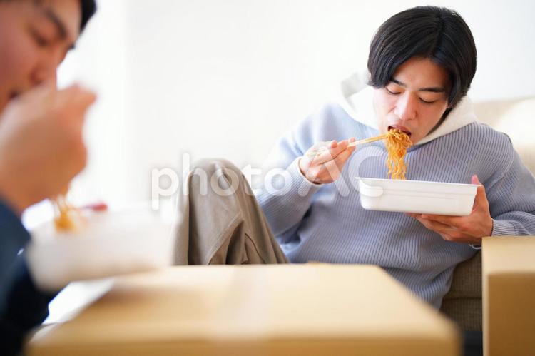 引っ越しの合間にカップ焼きそばを食べる2人の男性 引っ越し,一人暮らし,男性の写真素材