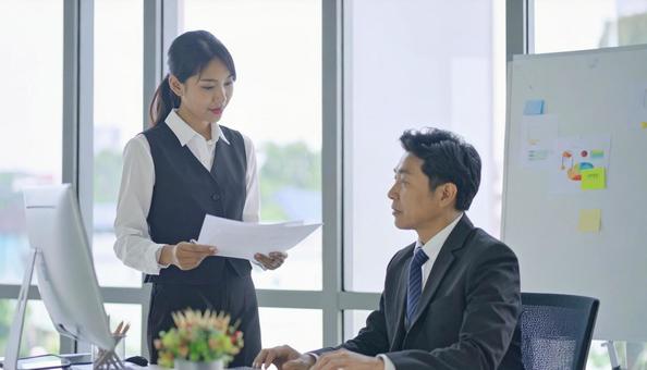 上司に報告する女性社員の写真