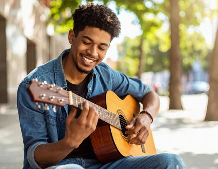 路上でギターを奏でる青年の写真