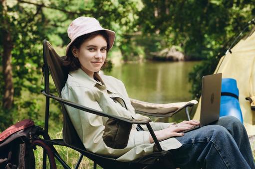 黒い椅子に帽子をかぶって座る人物 女性,外国人,キャンプの写真素材