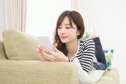 ソファーでスマホを使う女性 ソファーでスマホを使う女性 スマホ,女性,人物の写真素材