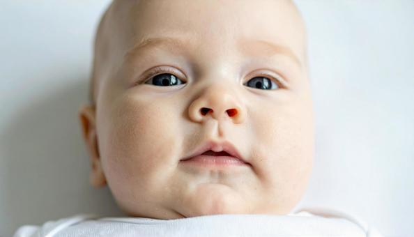 あおむけで寝ている赤ちゃんの顔のアップの写真