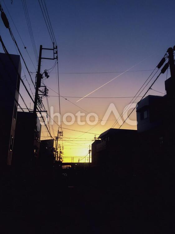 ビルの間の夕陽と飛行機雲 夕陽,飛行機雲,夕方の写真素材