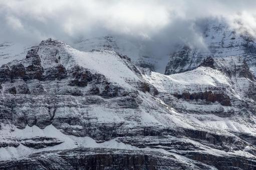 雪の岩山｜雲間から光差す 山,ロッキー,カナダの写真素材