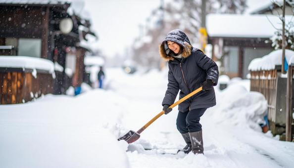大雪が降った日の翌日の朝に雪かきする女性 大雪が降った日の翌日の朝に雪かきする女性の写真