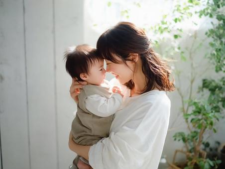 室内で赤ちゃんを抱いて微笑む幸せな母親 室内で赤ちゃんを抱いて微笑む幸せな母親の写真