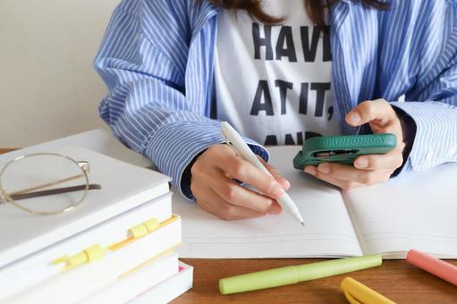 スマホで勉強をする女性 スマホで勉強をする女性の写真