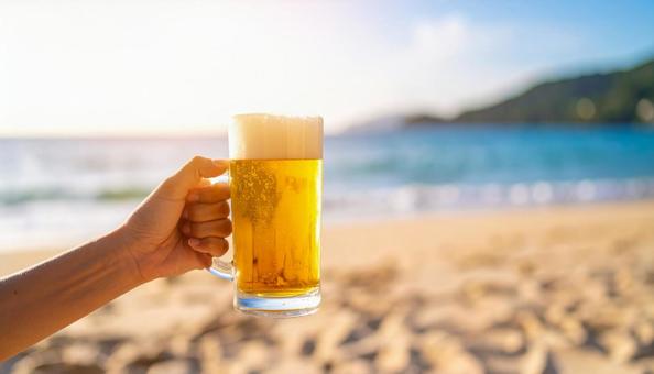 ビーチでビールジョッキを持つ手元 ビーチでビールジョッキを持つ手元の写真