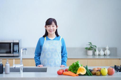 キッチンで新鮮な野菜と笑顔の中年女性 キッチンで新鮮な野菜と笑顔の中年女性の写真