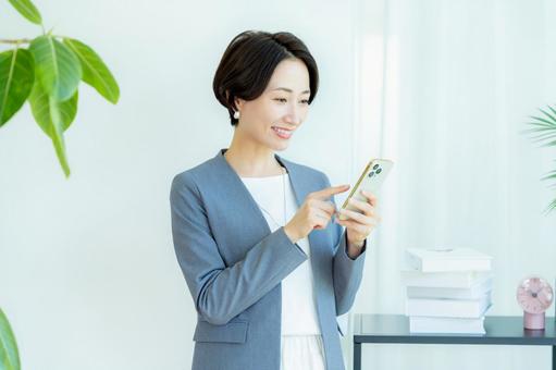 スマホを操作するビジネスウーマン スマホを操作するビジネスウーマン スマホ,笑顔,ビジネスウーマンの写真素材