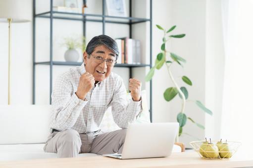 パソコンで嬉しいシニアの男性 パソコンで嬉しいシニアの男性の写真